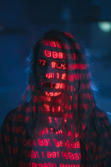 Close-up photograph of a computer screen displaying lines of colorful code with HTML tags in shades of yellow, green, blue, and red on a dark background. The code appears to be part of a web developme
